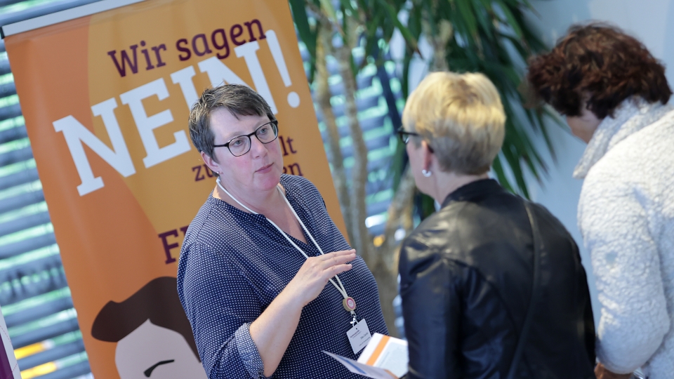 zwei Frauen sprechen vor einem Plakat mit der Aufschrift "Wir sagen Nein"