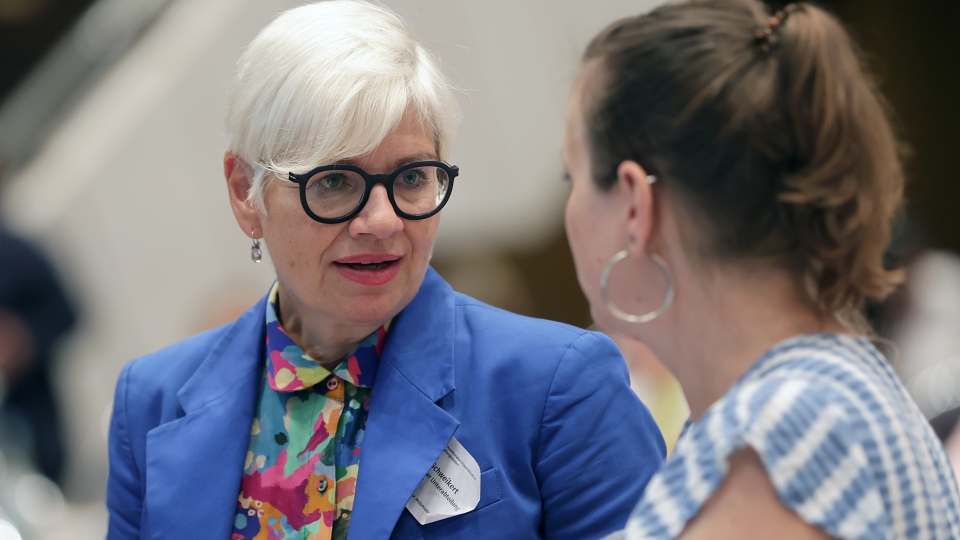 eine blonde Frau mit Brille unterhält sich mit einer Frau mit Pferdeschwanz